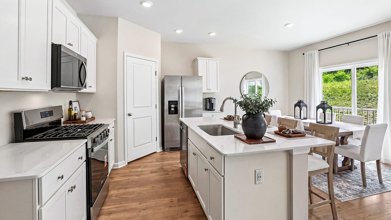 Kitchen view with island seating potential, stainless steel appliances, and open sightlines into the living area.