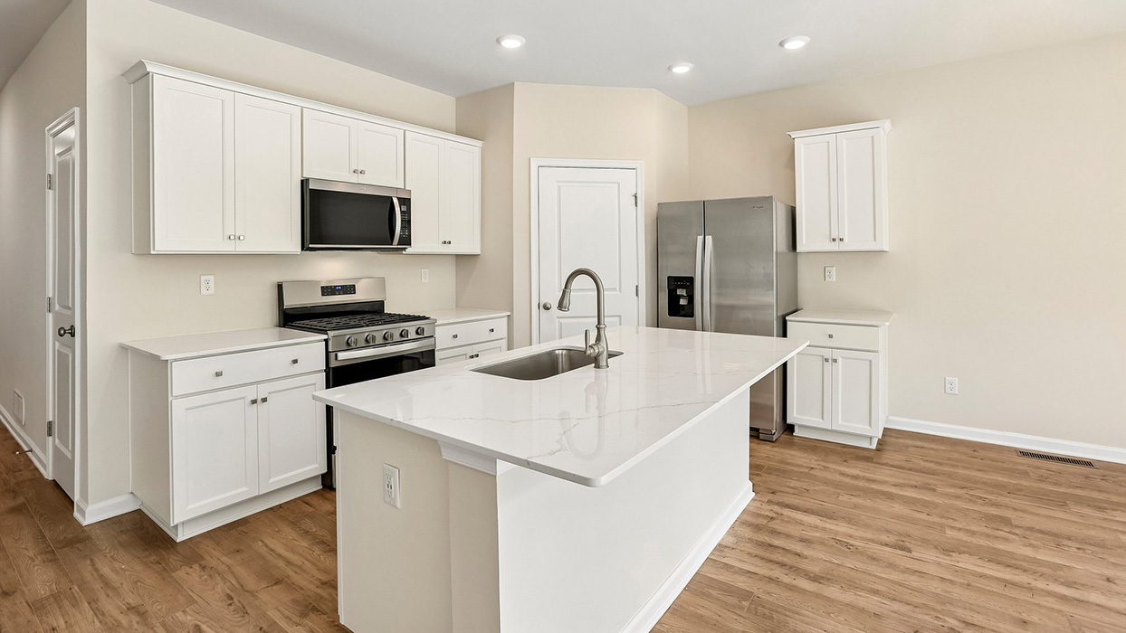 Bright kitchen with island sink, gas range, microwave above, and sliding glass door leading to outdoor space.