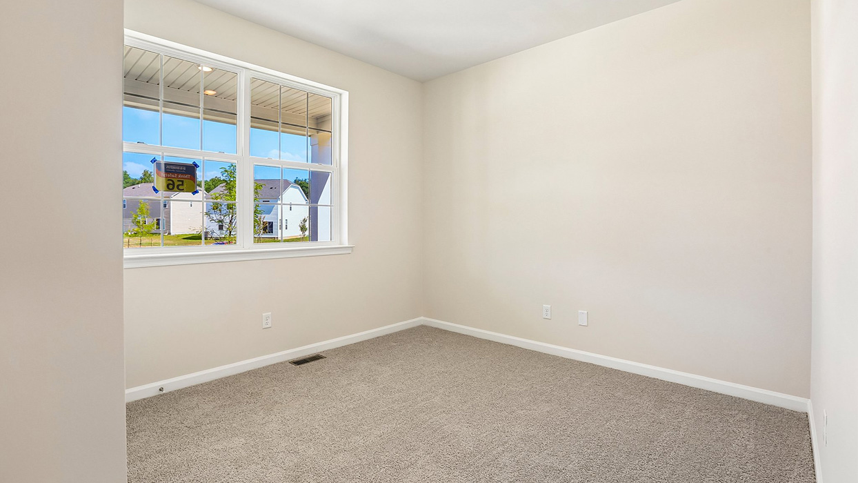 Secondary bedroom or office space with carpet flooring, large window, and simple neutral finishes.