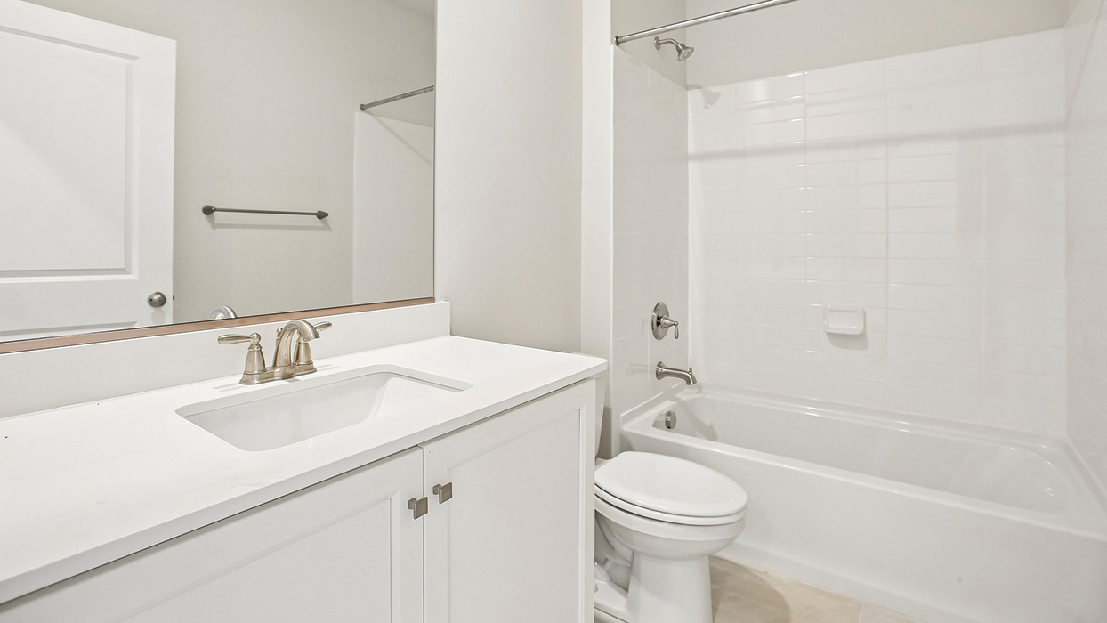 Full bathroom with single vanity, white cabinetry, and tub-shower combo with tile surround.