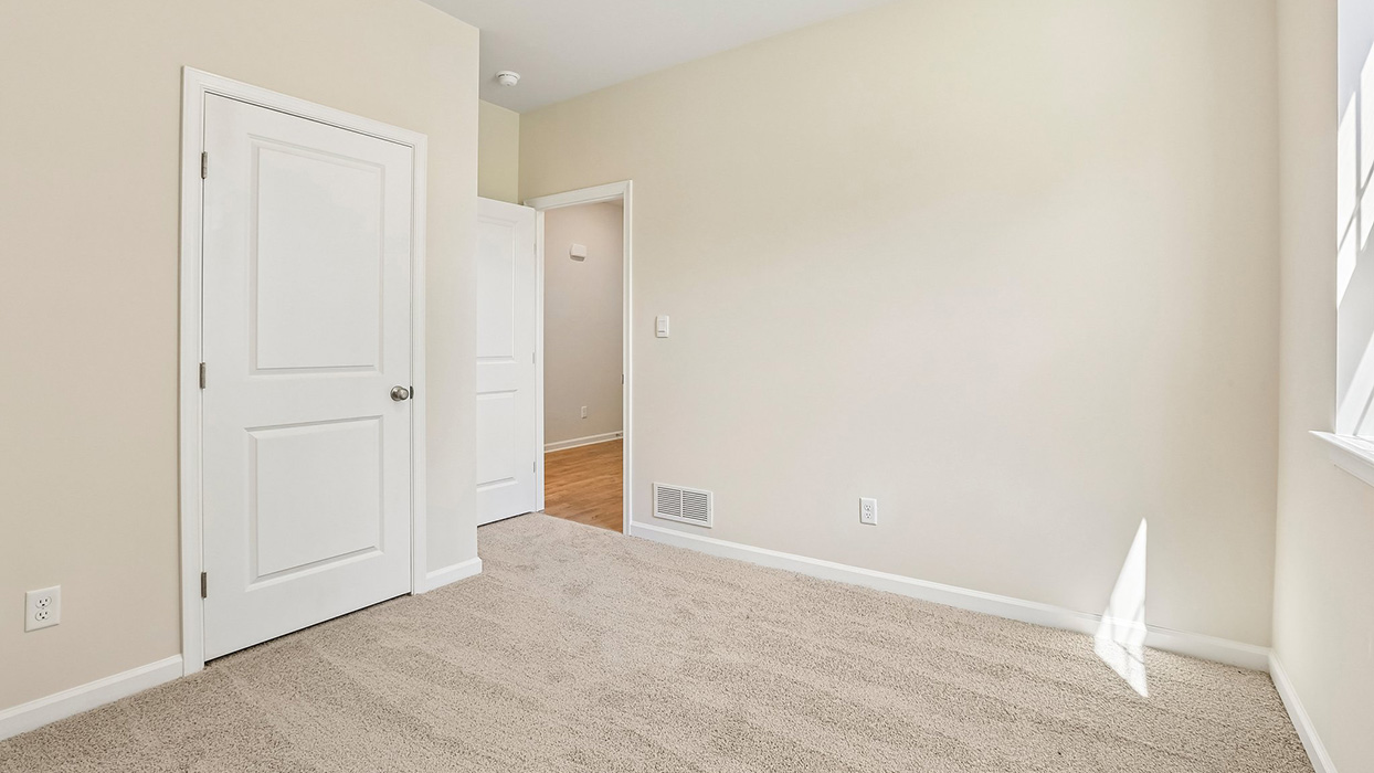 Bedroom with carpet flooring, closet door, and direct access to hallway with wood-look flooring.