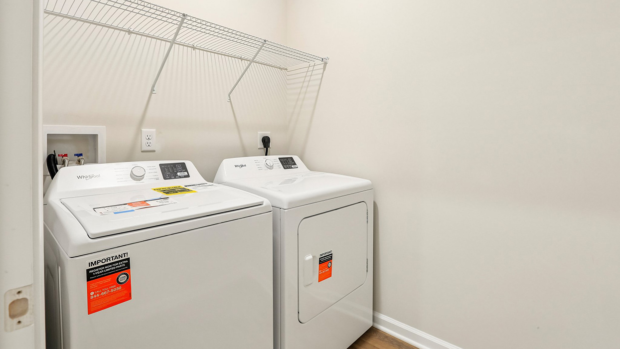Laundry room with washer and dryer, overhead wire shelving, and dedicated utility connections.