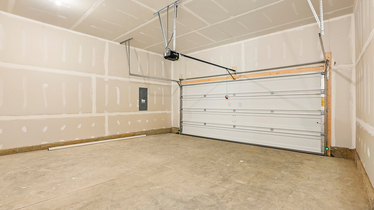 Two-car garage interior with concrete flooring, overhead door, and opener system.