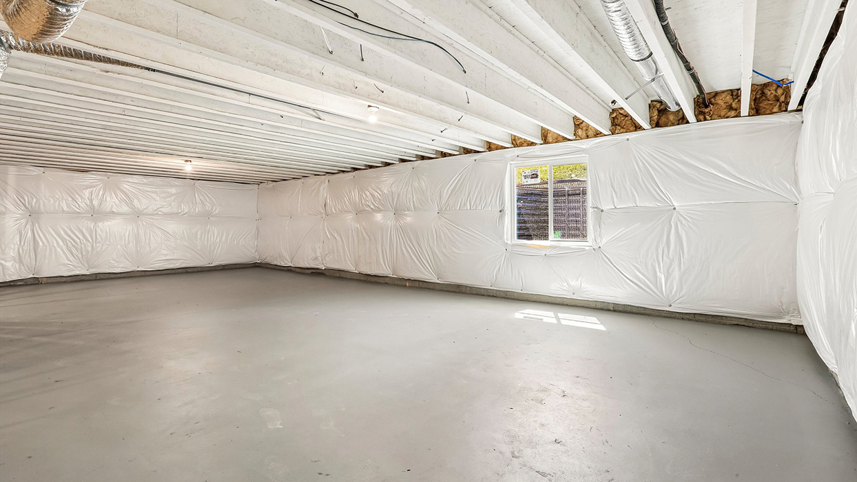 Unfinished basement with concrete floors, insulated walls, and window for natural light.