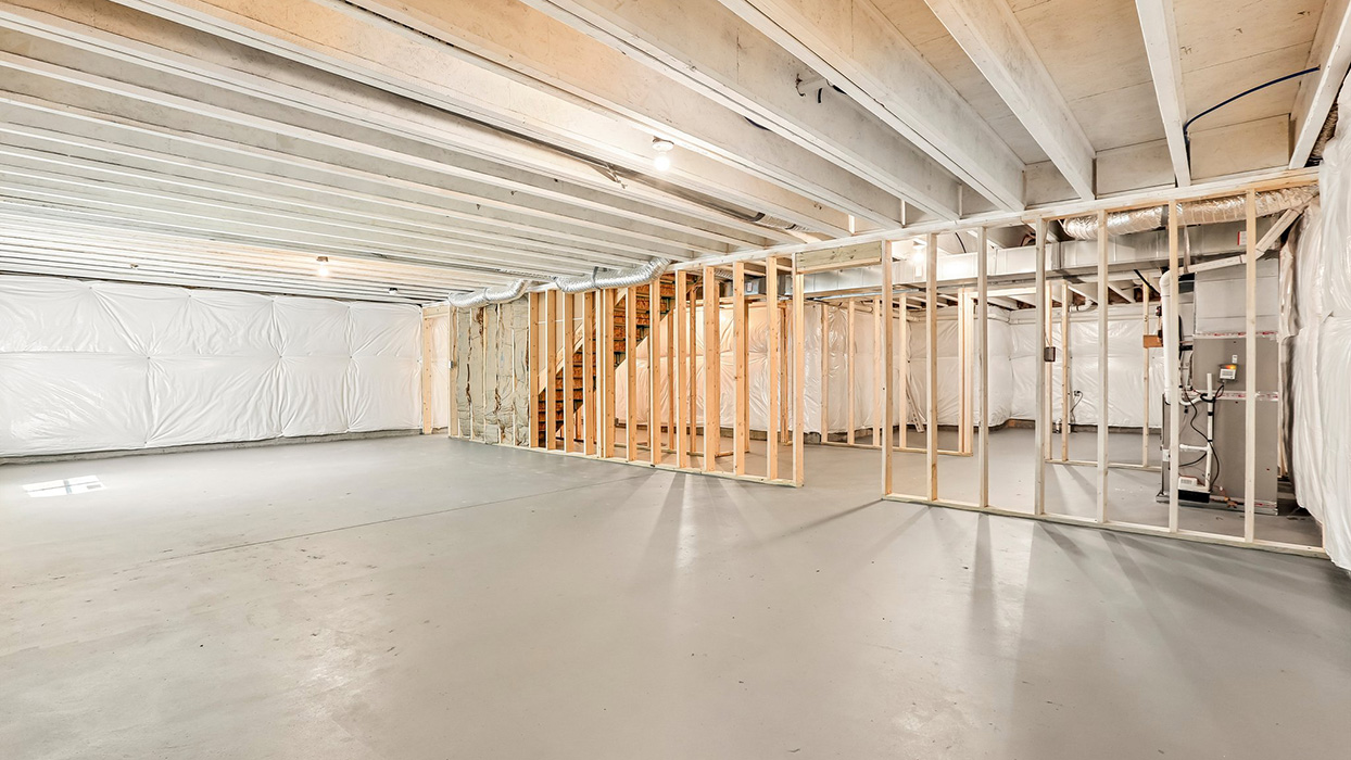 Basement with framing in place, exposed beams, and open layout for future finishing options.