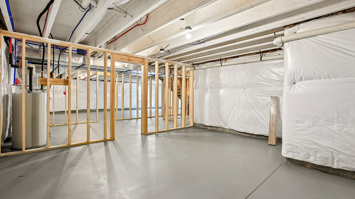 Basement mechanical area with framed sections, visible ductwork, and open concrete floor space.