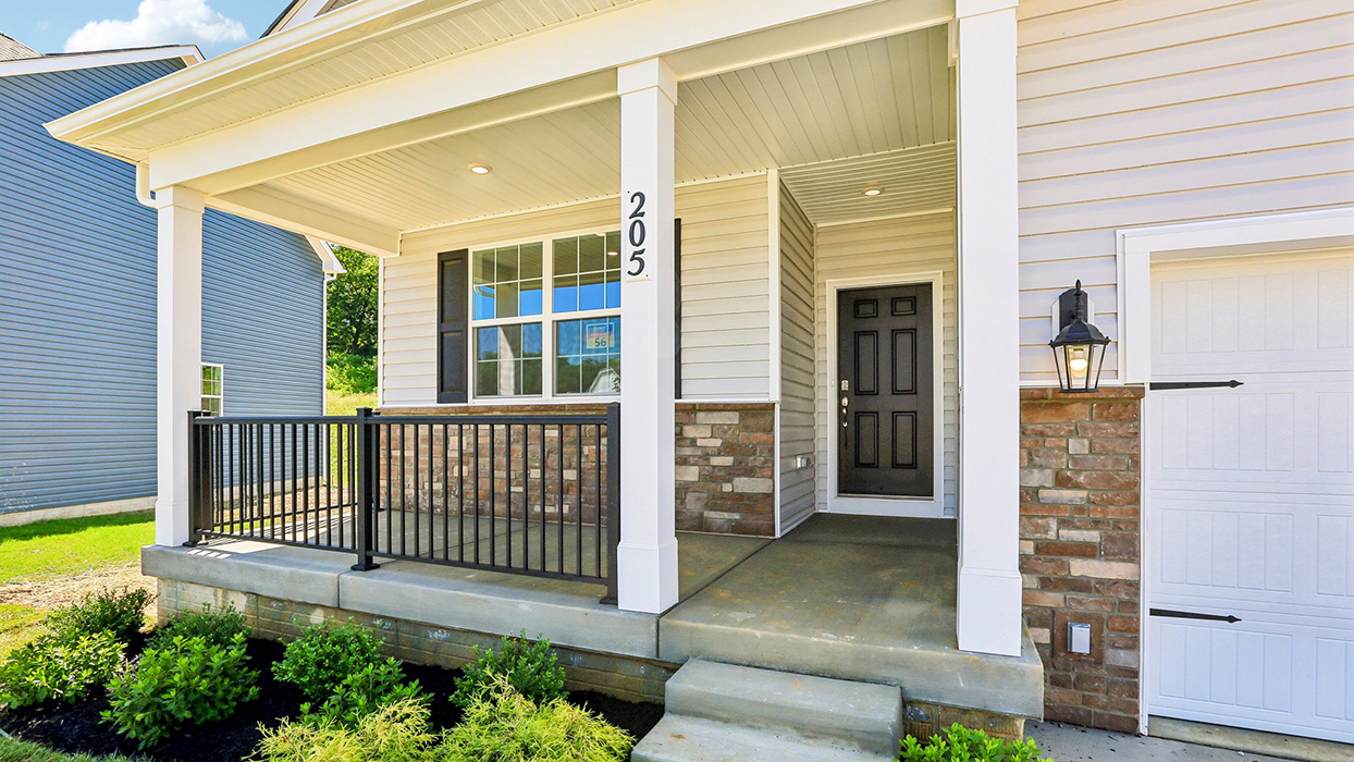 overed front porch with white columns, black railing, and concrete steps leading to a recessed entry with dark front door.