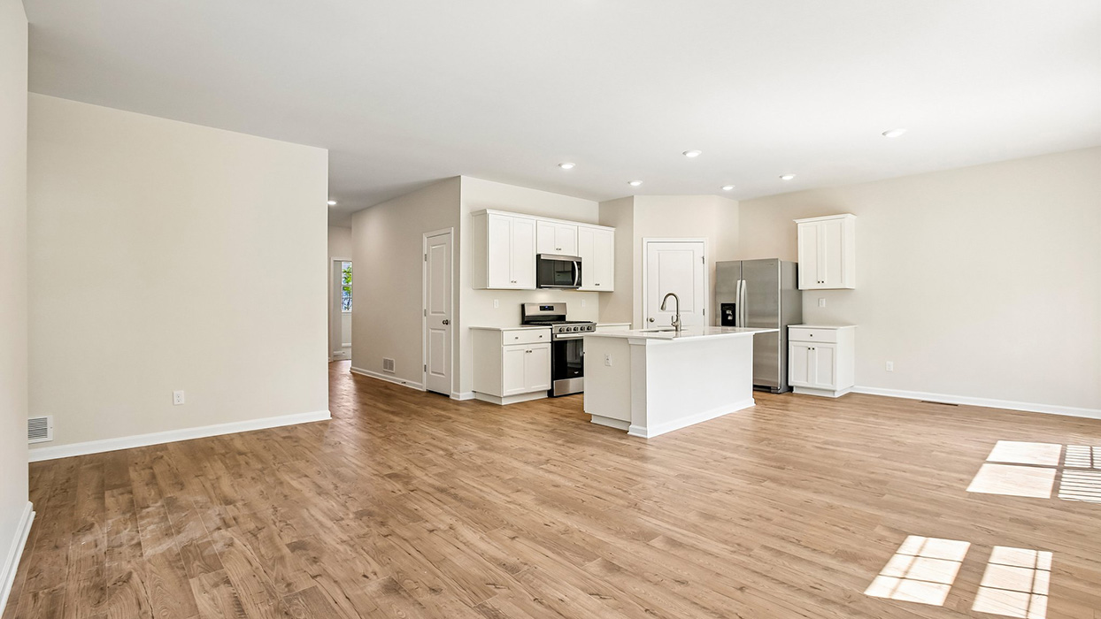 Open-concept living and kitchen area featuring recessed lighting, white cabinetry, and a central island with sink.