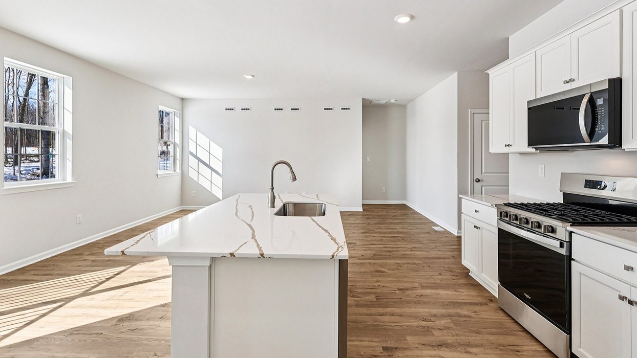 Kitchen area with stove to the right and living area in the back.