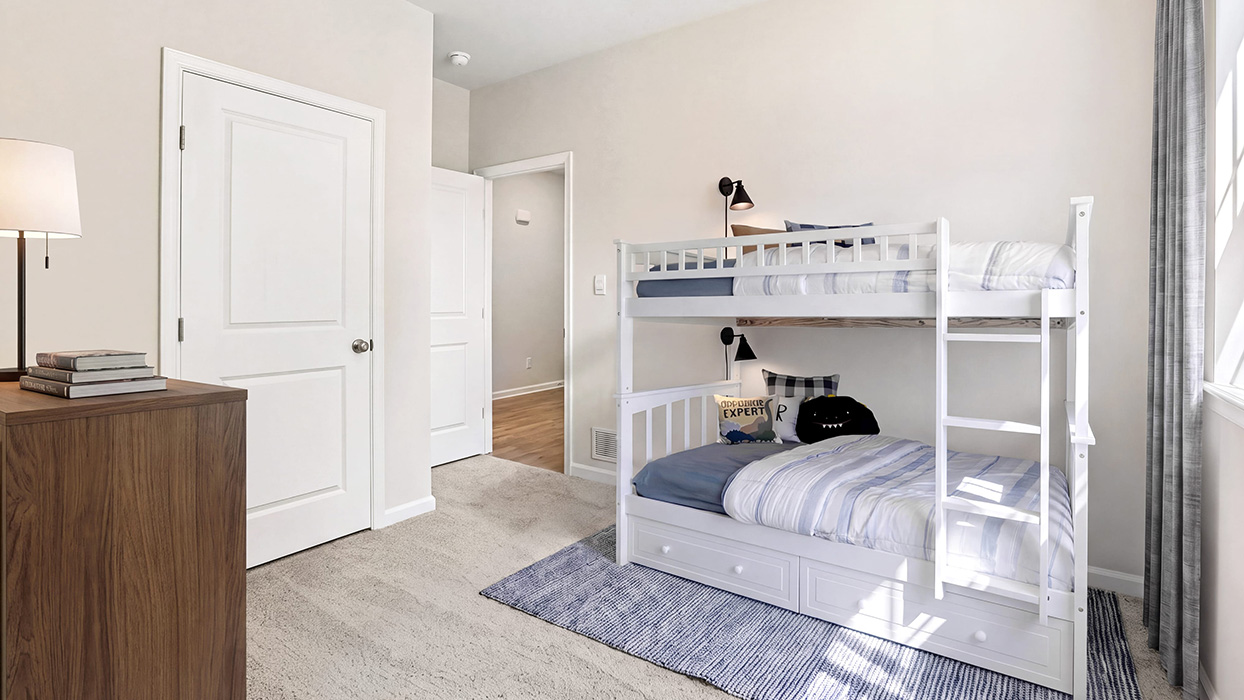 Bedroom with carpet flooring, closet door, and direct access to hallway with wood-look flooring.