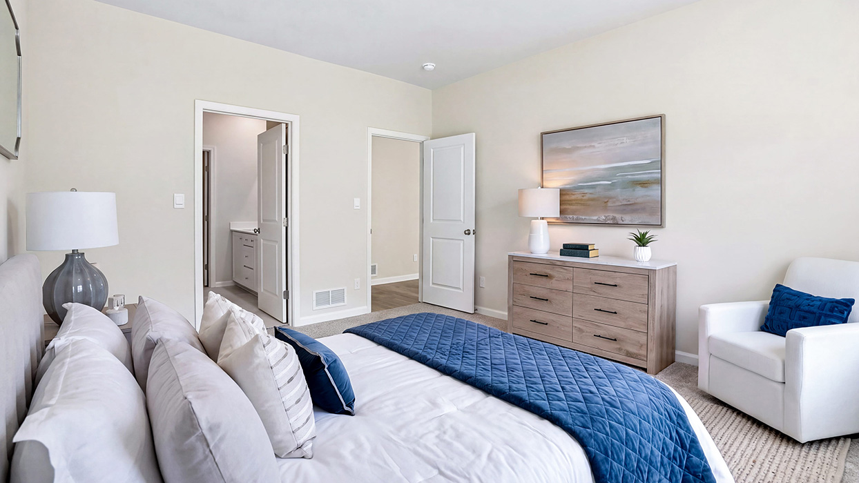 Primary bedroom showing entry to en-suite bath and closet with neutral finishes and carpet flooring.