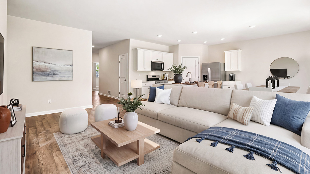 Open-concept living and kitchen area featuring recessed lighting, white cabinetry, and a central island with sink.