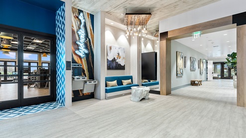 A transitional hallway with built in seating, large artwork, and an eye-catching light fixture within Amblebrook's community center.