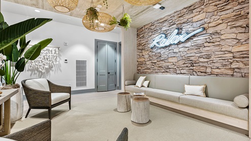 Relaxation room in the Amblebrook amenity center with a built in bench and accent chairs, plants, a stacked-stone accent wall, and soothing color palette.