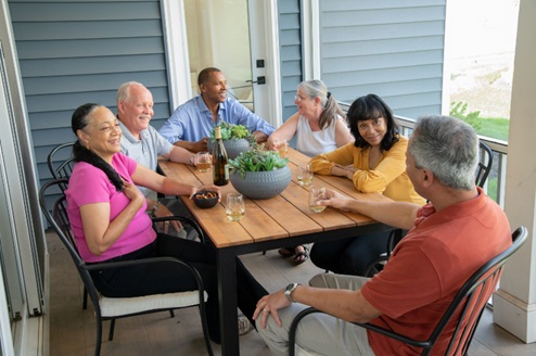 Lifestyle image of a group of adult friends gathered around a table chatting with wine and snacks.