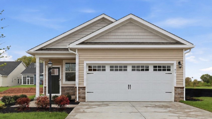 A Bown home with cream siding,  white trim, and white two car garage ith carriage style hardware