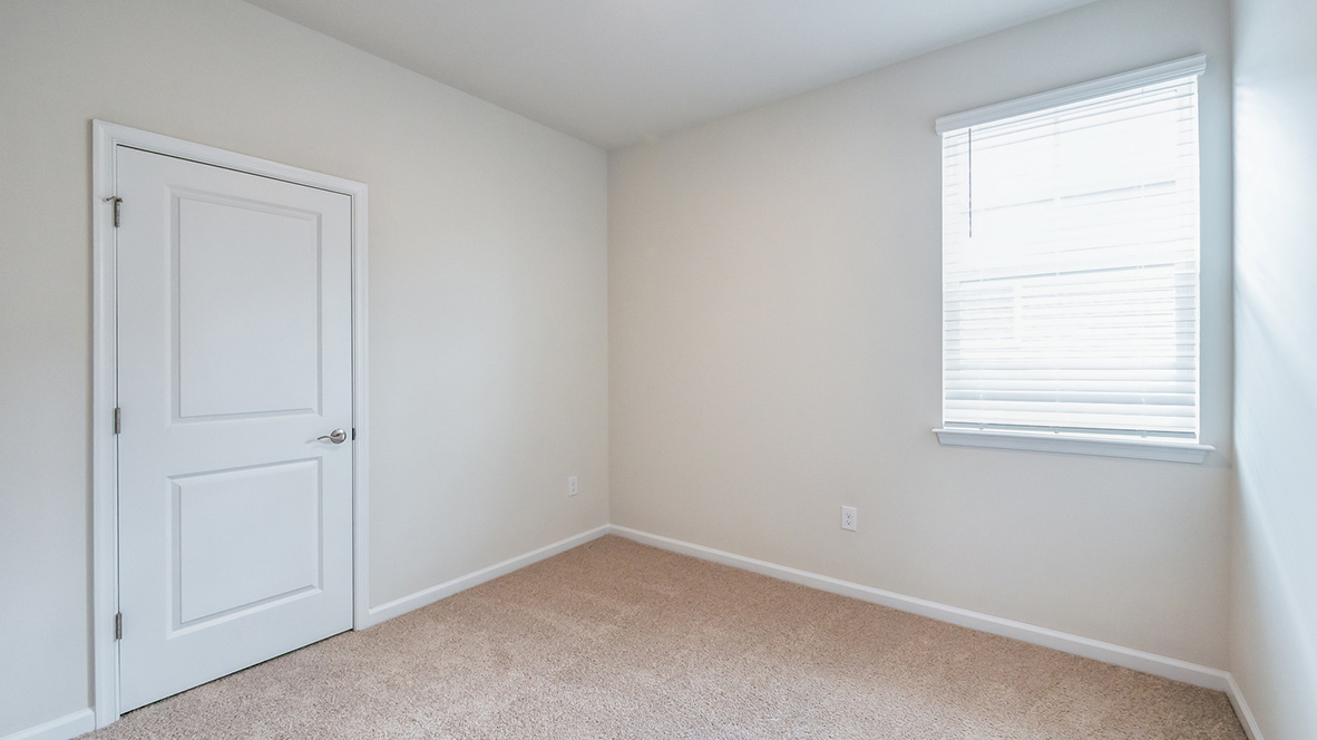 A secondary bedroom with one window and single closet door.
