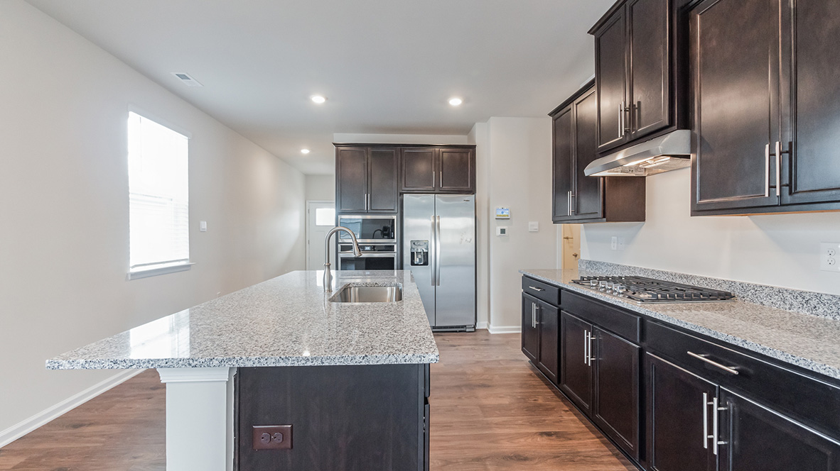 The open-concept kitchen has espresso colored kitchen cabinets.