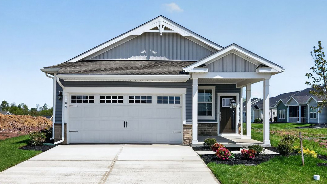 A front facing photo of a Bowen home with gray siding, white trim, and white two car garage door carriage style hardware