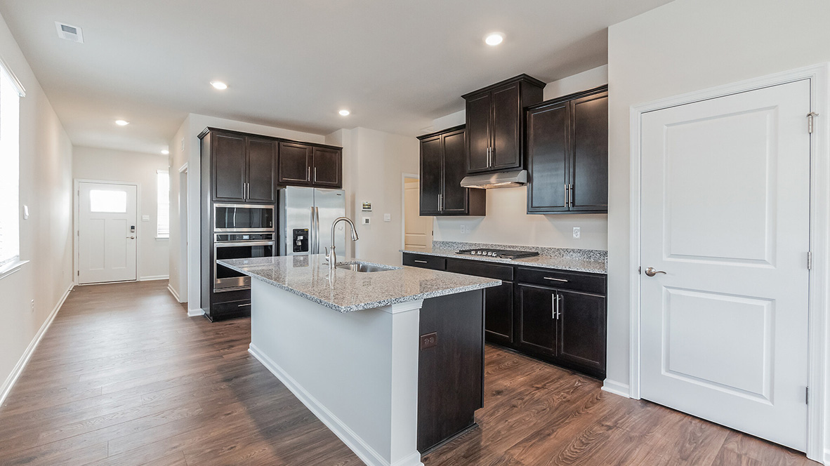 A view into the kitchen area and eat-in island with staineless steel appliances.