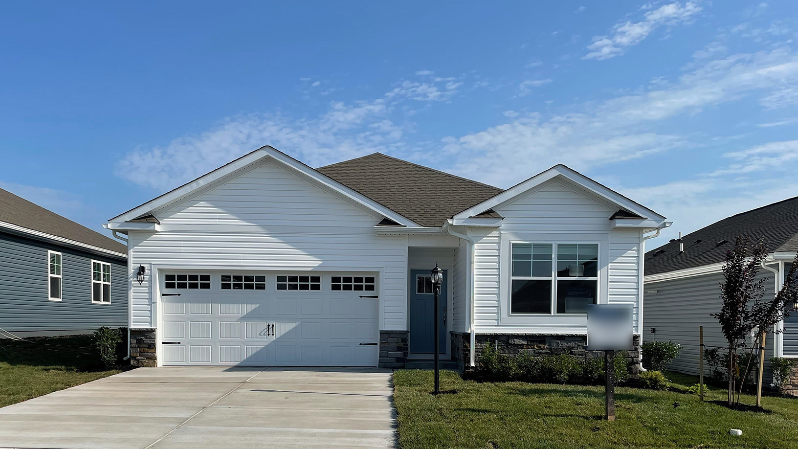 A photo of a Merrit home with white siding, white trim, and white two car garage