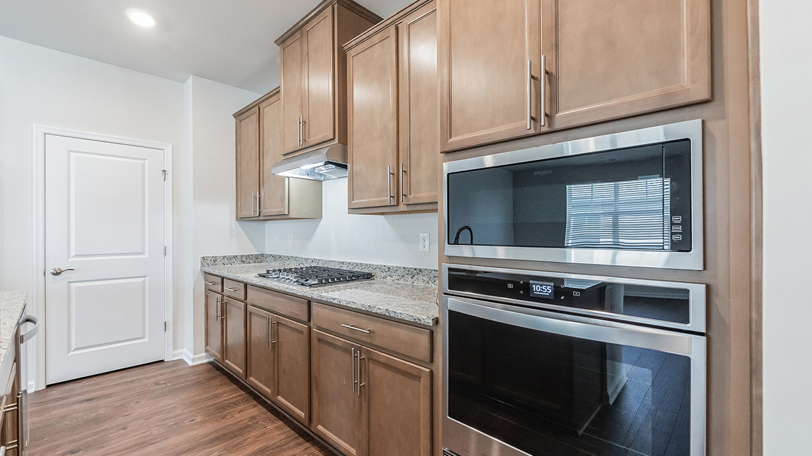 The kitchen with tan colored cabinets and stainless steel appliances.