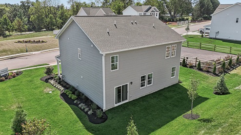 An aerial rear view of a two-story home with horizontal plank siding in complimentary colors of taupe and cream.