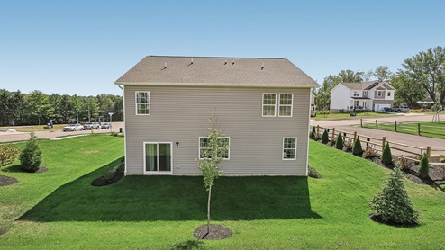 A rear view of a two-story home with horizontal plank siding in complimentary colors of taupe and cream.