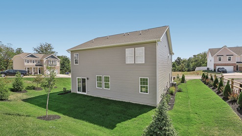 A rear view of a two-story home with horizontal plank siding in complimentary colors of taupe and cream.
