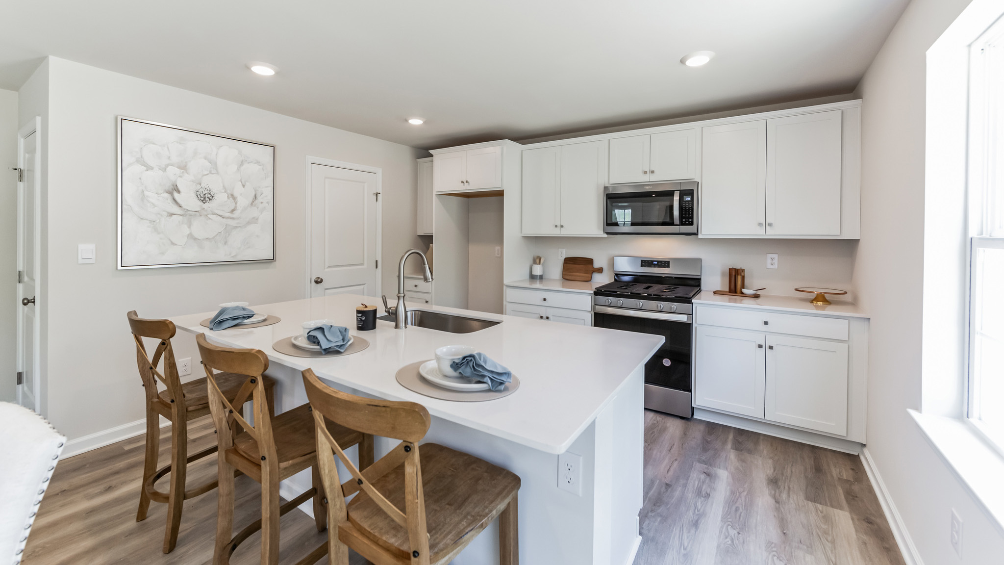 Open-concept kitchen with white cabinets and a large island.