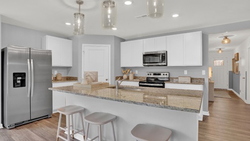 A large kitchen island with a sink is centered in the kitchen.