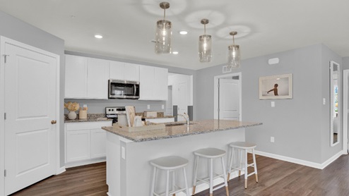 A large kitchen island with a sink is centered in the kitchen.