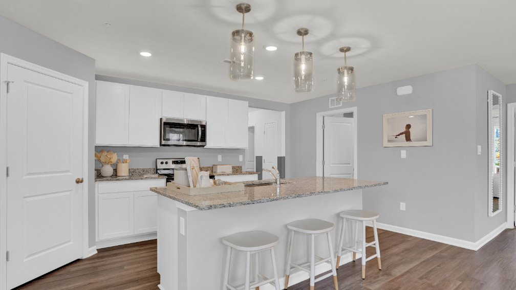A large kitchen island with a sink is centered in the kitchen.