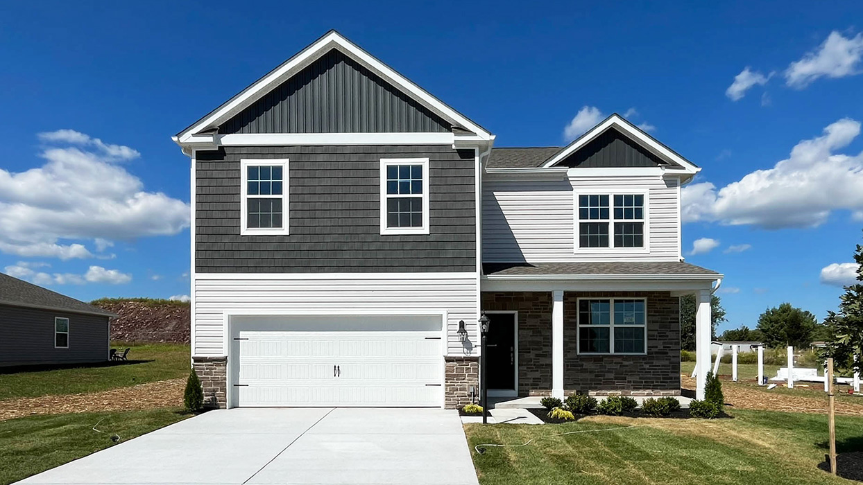 A image of a two-story Henley home with sterling siding, shake accent siding in storm blue, stone siding surrounding the porch and a stone kneewall surrounding a white two car garage.