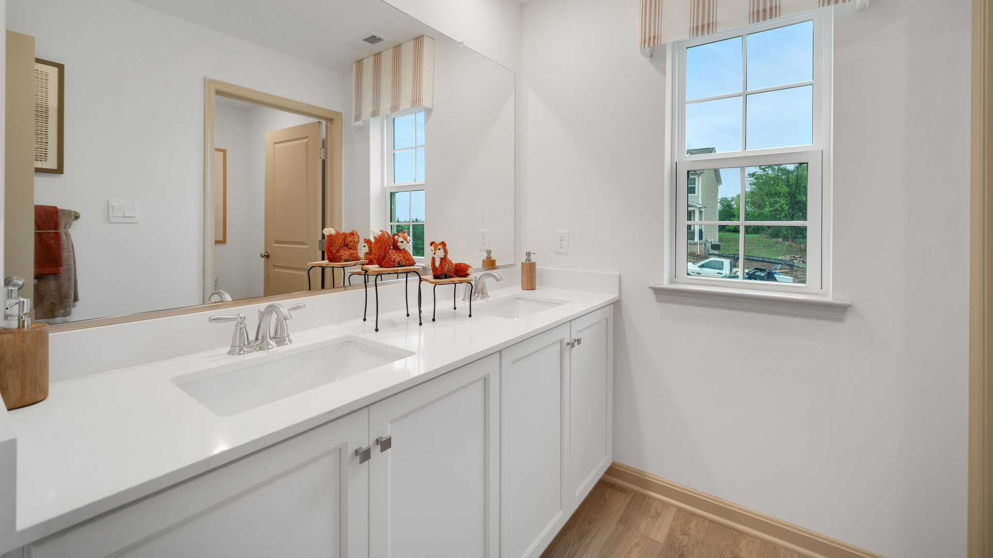 Spacious bathroom with a double vanity featuring white, shaker-style cabinetry and quartz countertops.