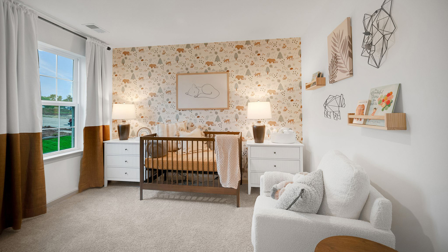 Secondary bedroom decorated as a nursery with a crib and two nightstands in front of a wallpapered accent wall and a comfy white accent chair.