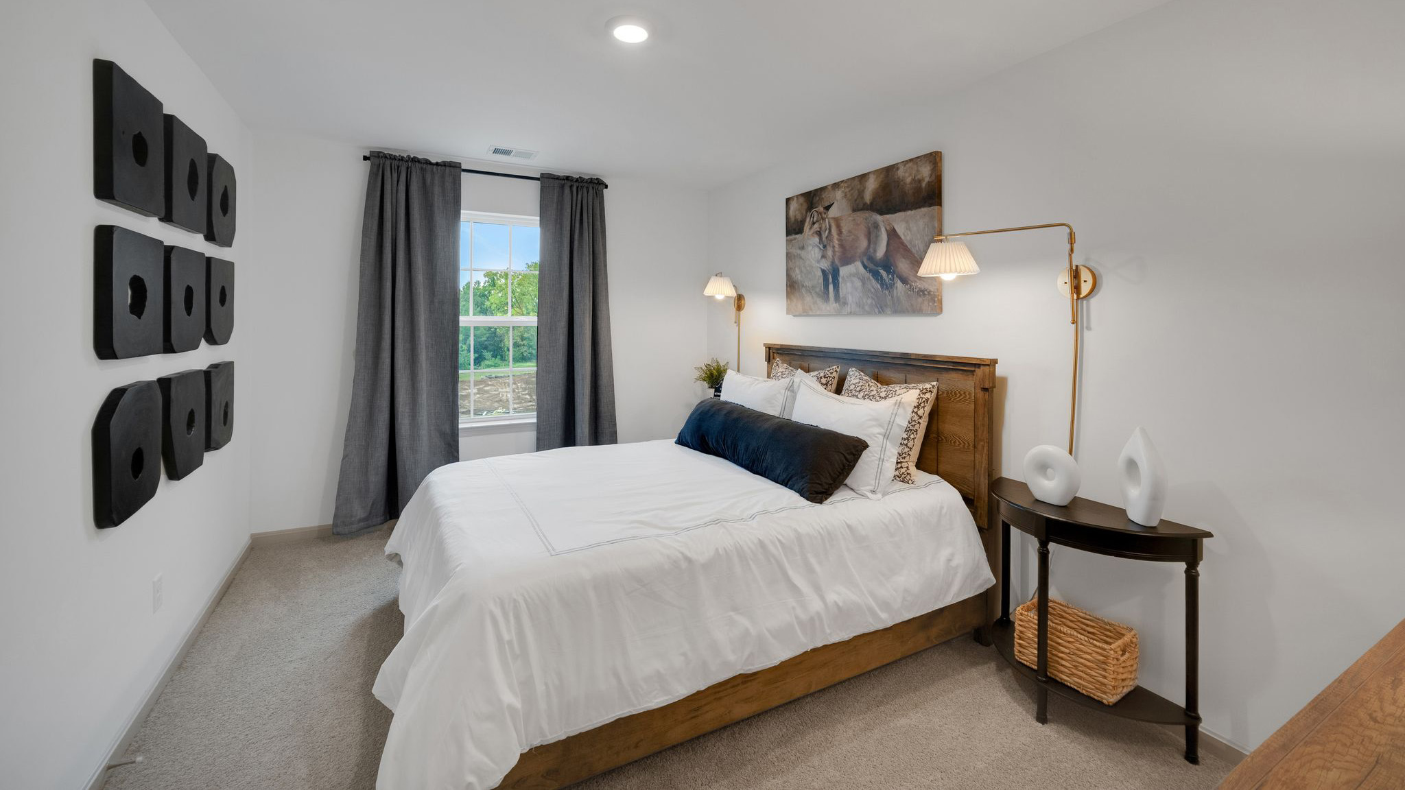 Secondary bedroom with a bed flanked by side tables and sconces in front of a window on the adjacent wall.