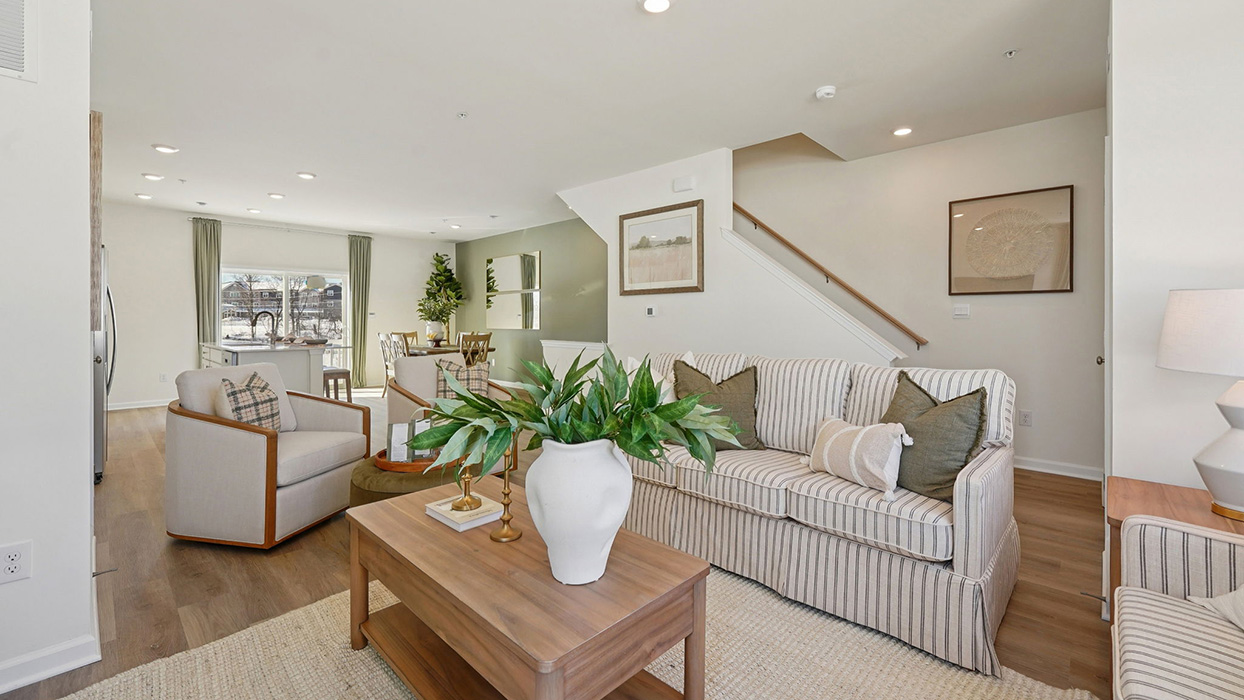 Living room with a large sofa a TV table with the stairwell to the bedroom level in the background