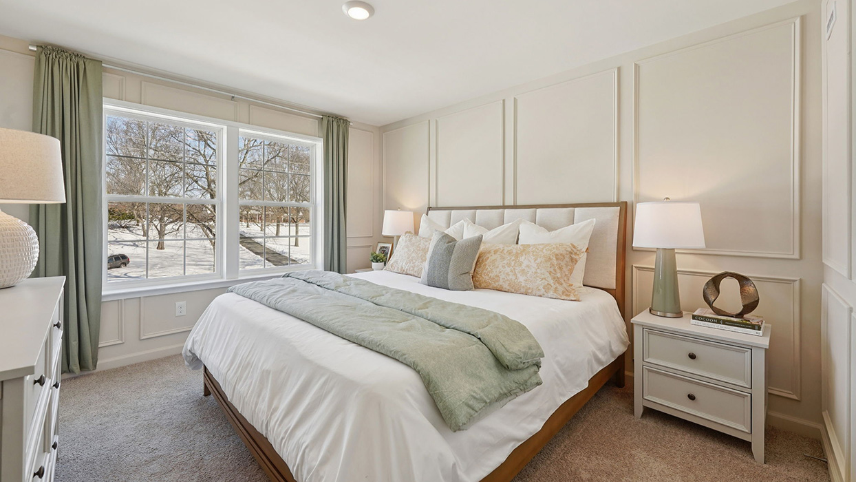 Primary bedroom with a king size bed and end tables and two large windows