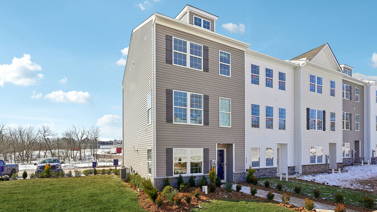 Exterior side image of the model townhome with harvard slate color siding dark gray shutters and a navy front door