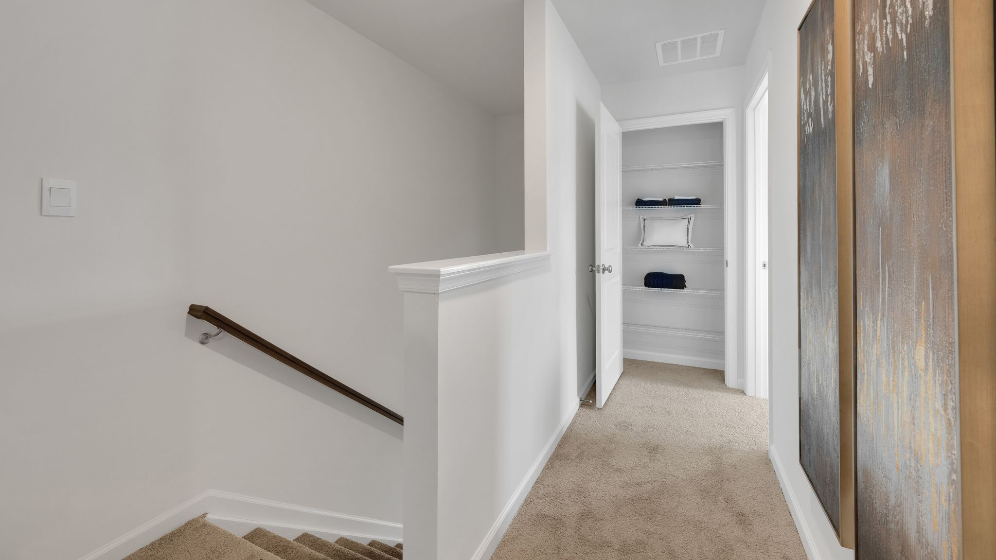 Top of the stairs looking down the hall to the extra closet next to the primary bedroom.