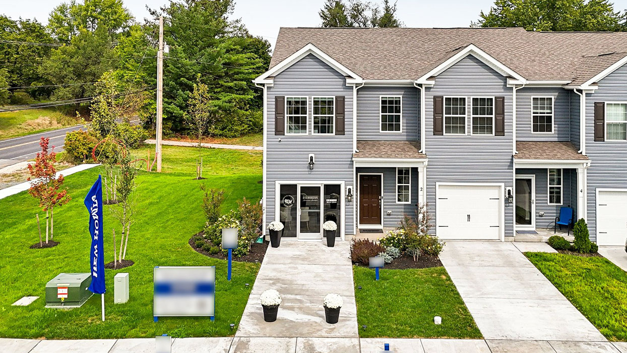 Exterior front image of the model townhome with dark gray horizontal paneling, black shutters, and a white single car garage.