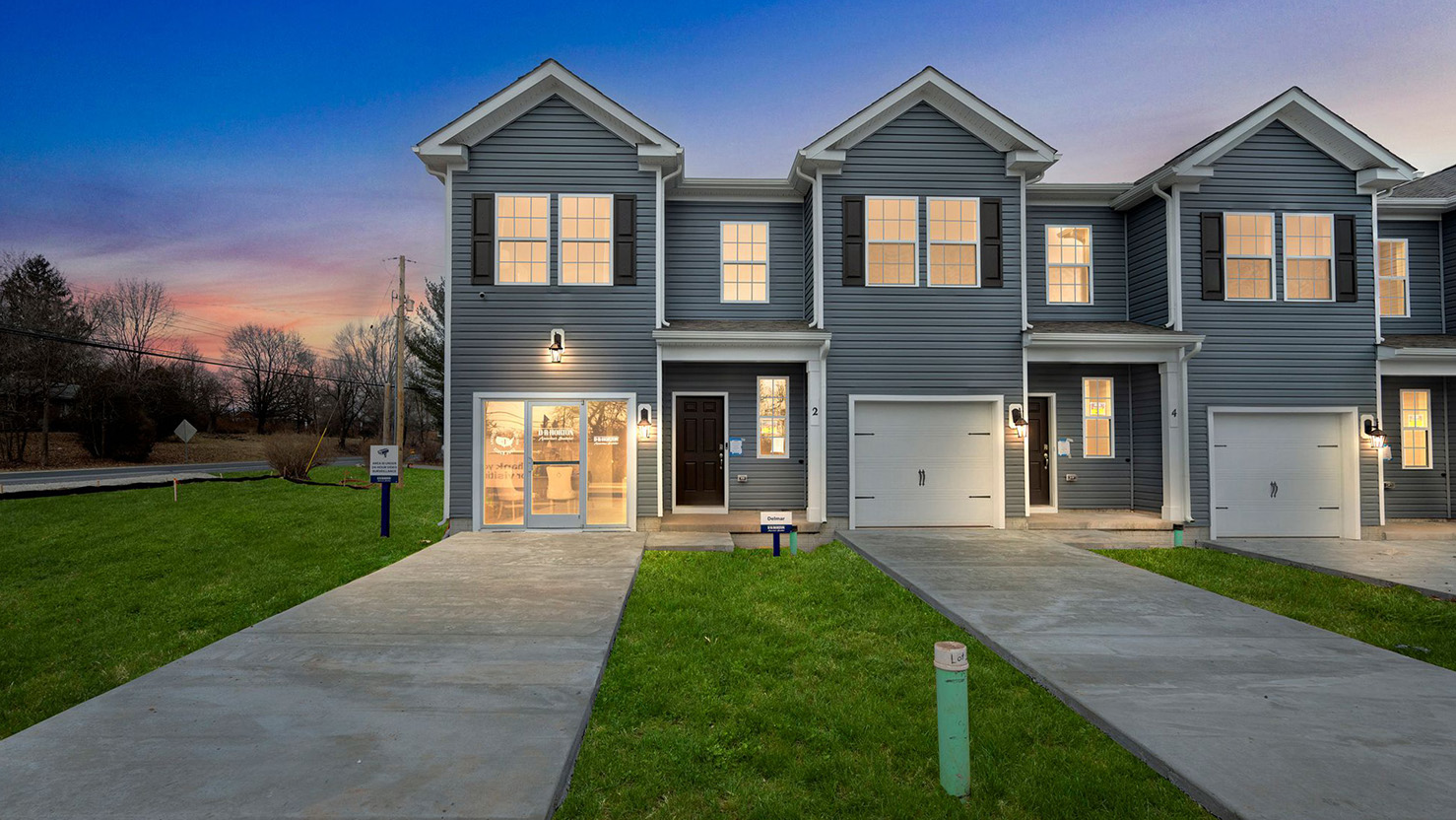 Exterior front image of the model townhome with dark gray horizontal paneling, black shutters, and a white single car garage.