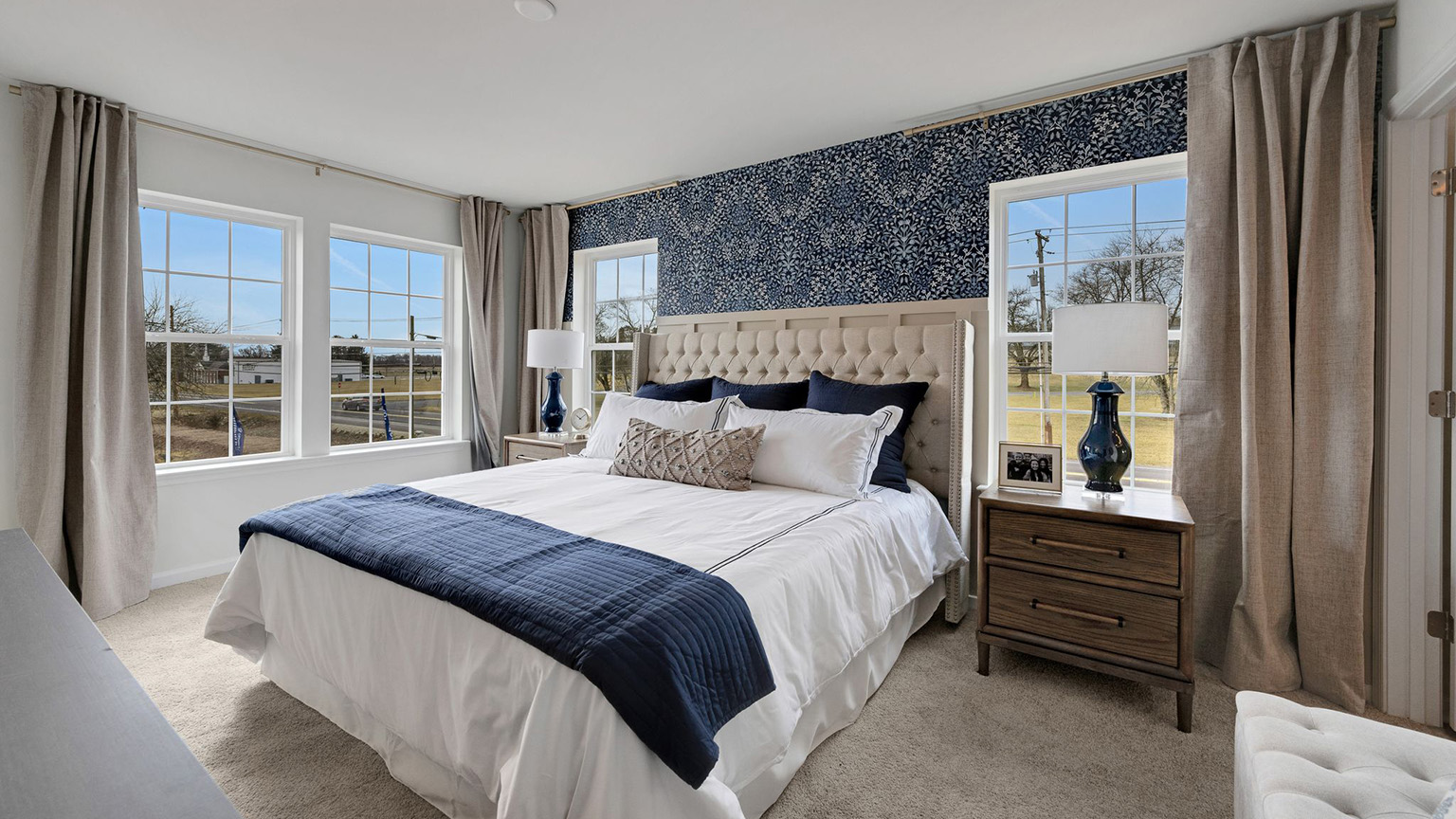 Primary bedroom with large double window and two windows on either side of the bed.