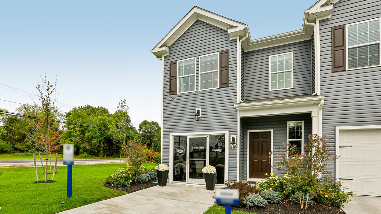 Exterior front image of the model townhome with dark gray horizontal paneling, black shutters, and a white single car garage.