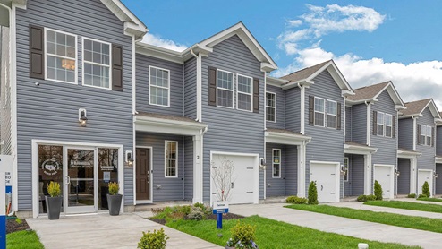 Exterior front image of the model townhome with dark gray horizontal paneling, black shutters, and a white single car garage.