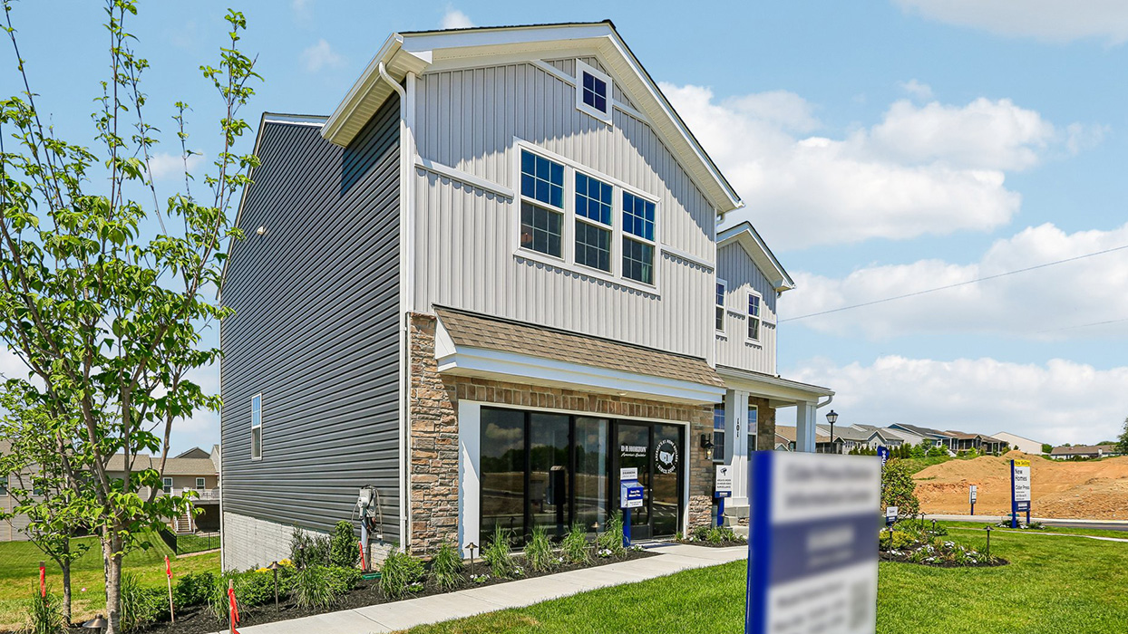 A sidewalk view side-angle of a two-story Galen home with ironstone siding, stone front with inviting walkway.