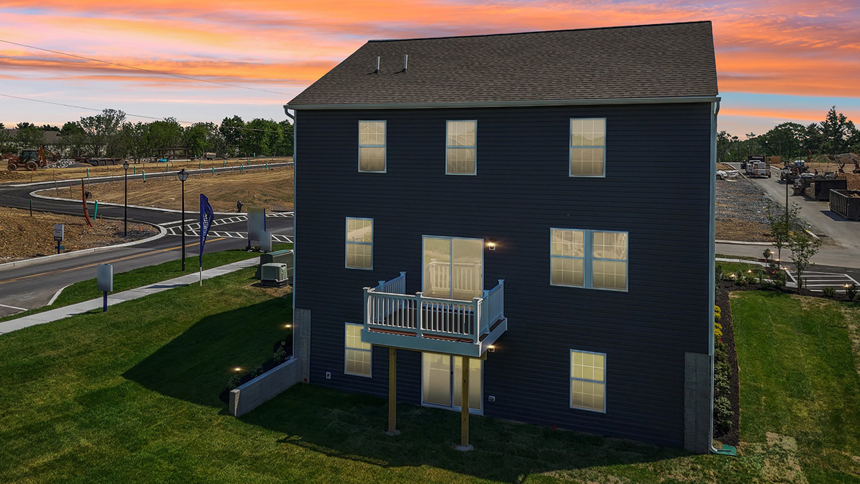 A dusky aerial rear view of a two-story Galen home with ironstone siding, six windows, and walkout basement.