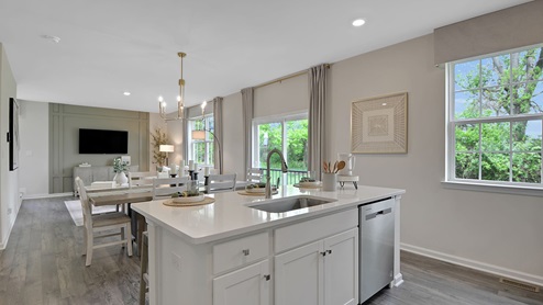 Open concept view of the kitchen, dining, and living area. View of the inside of the island with sink and dishwasher.