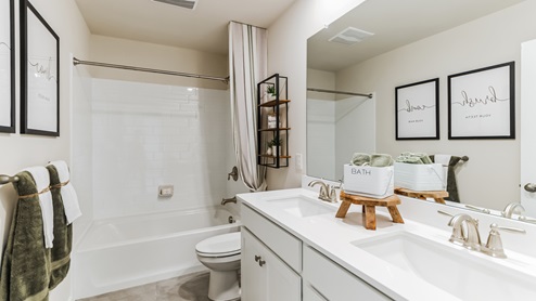 Full bathroom with tub and shower connected, double sink with storage below sinks.